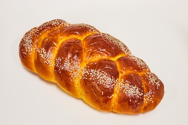 Greek bread braided with white seeds on a white background