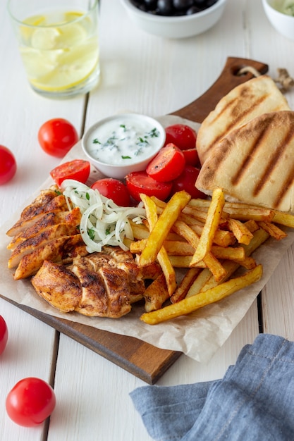 Greek dish gyros with chicken, french fries, tomatoes, onions and pita. Greek cuisine.