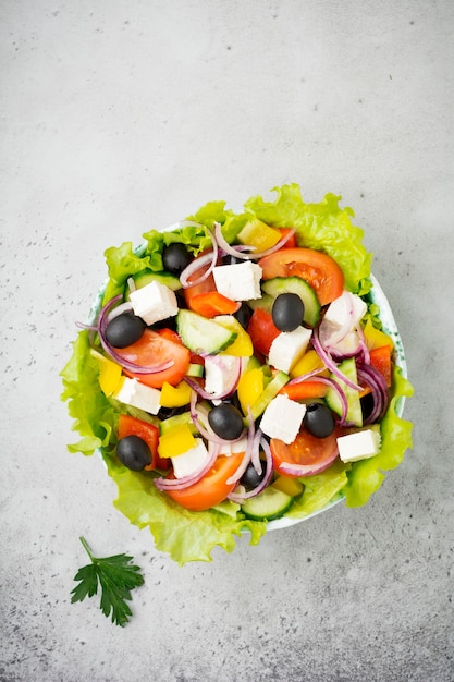 Greek salad in  ceramic plate on gray concrete