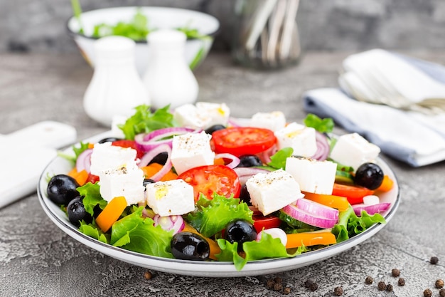 Photo greek salad fresh vegetable salad with tomato onion cucumbers pepper olives lettuce and feta cheese greek salad on plate