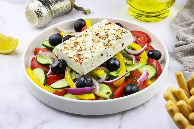 Greek salad in a plate on a grey marble background. Restaurant dish. Vegetable salad with olive oil