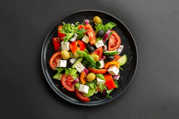 Greek salad top view on black table over black table background