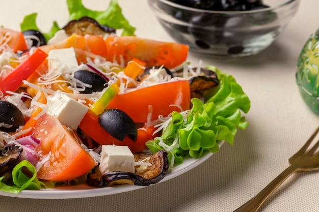 Greek salad with feta cheese, tomato, lettuce and black sun-dried olives close-up.