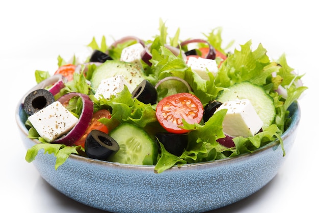 Greek salad with feta, olives, tomatoes and cucumbers isolated on a white background, close-up