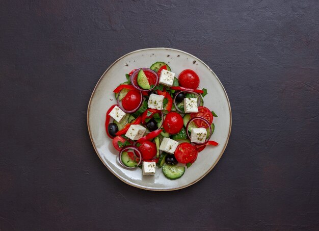 Greek salad with tomatoes, cucumbers, cheese, onions, peppers and olives