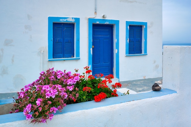 Greek white house with blue door and window blinds oia village on santorini island in greece