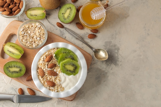 Greek white yogurt with kiwi almonds and oatmeal on a light concrete table