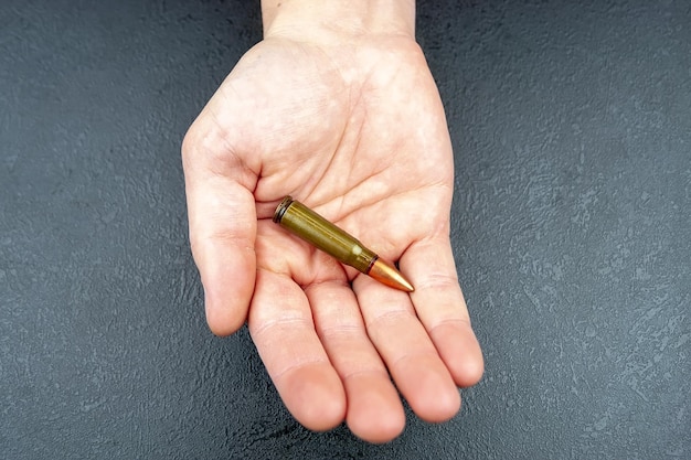 A green 762 mm cartridge for a Kalashnikov assault rifle lying in a man's hand