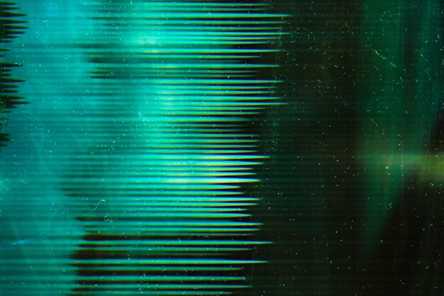 Green aged filmstrip. Distressed texture. Dust scratches on dark glowing surface.