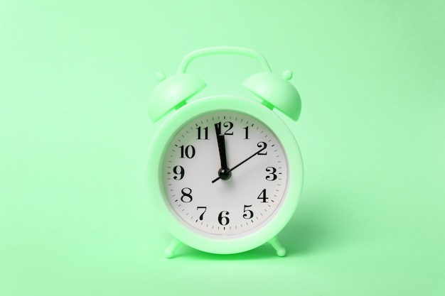 Green alarm clock morning wake-up time. Trendy minimal style. Beauty and fashion concept.