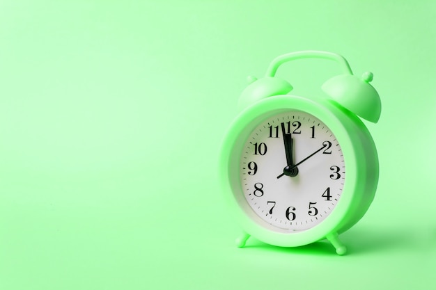 Green Alarm clock on pastel green background. Time concept. Copy space.