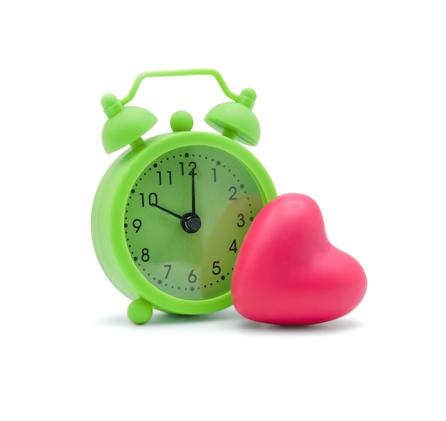 Green alarm clock with pink heart on white with copy space Time for love and a healthy concept