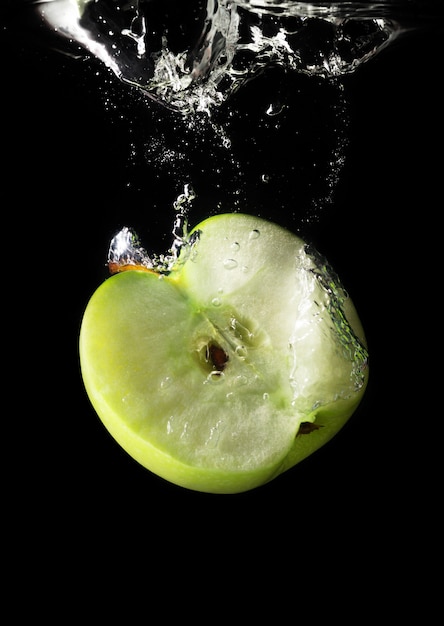 Green apple dropping into water 