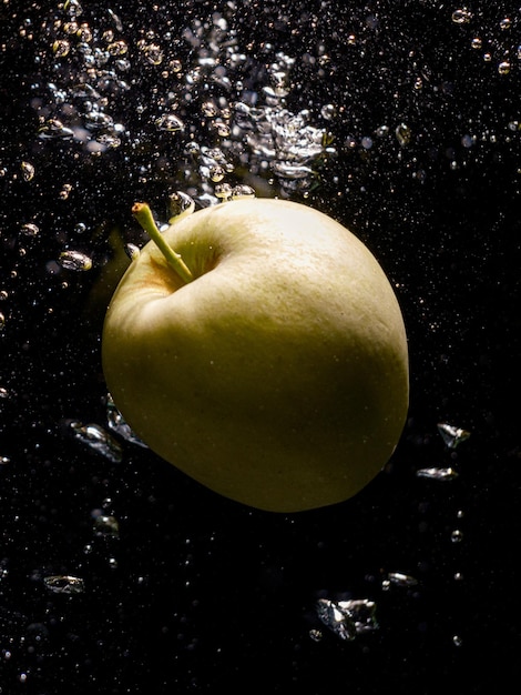 Green apple falling in water