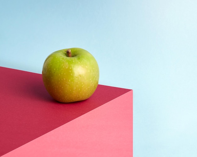 The green apple is on a multicolored abstract background