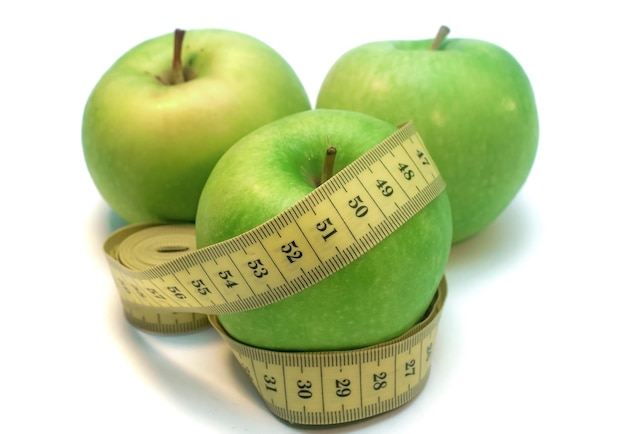 Green apple wrapped by measuring tape isolated on white background