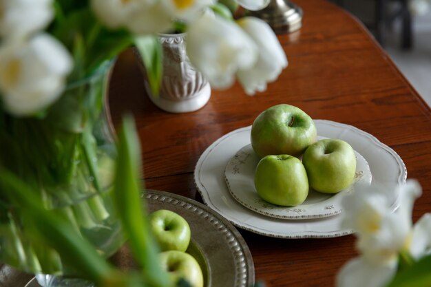 Green apples on a porcelain plate on the table