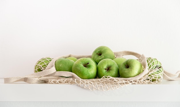 Green apples in a string bag on a white background