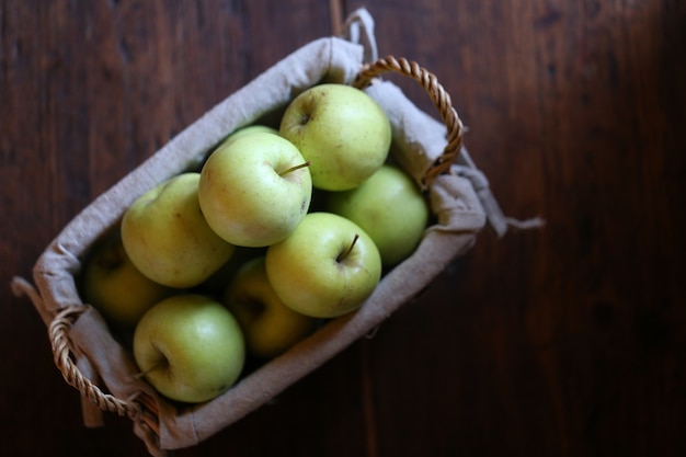 Green apples in wicker basket top view. Organic fresh apples from the garden.