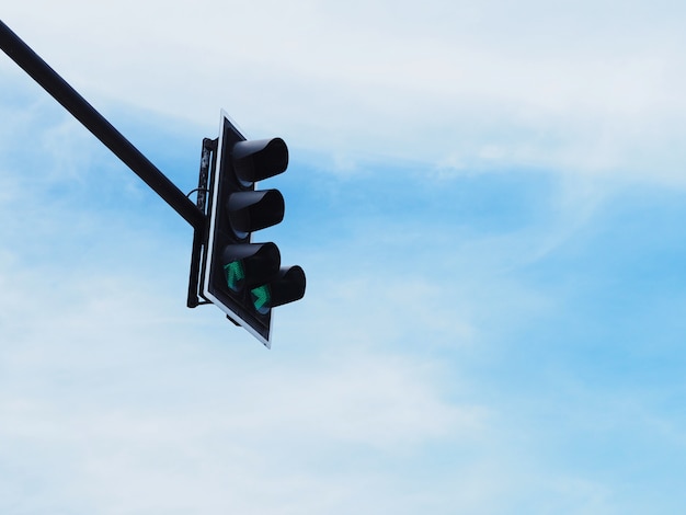 Green arrow symbol on traffic light against blue sky