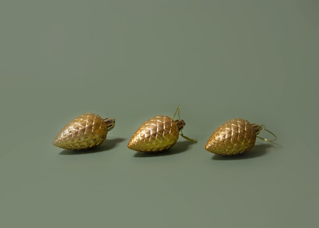 On a green background there are three golden Christmas tree toys cones a place for text