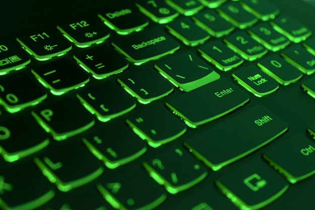 Green backlit laptop keyboard, hacking and blockchain concept