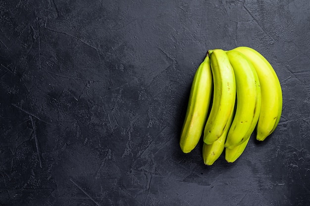 Green bananas. Black background. Top view. Space for text