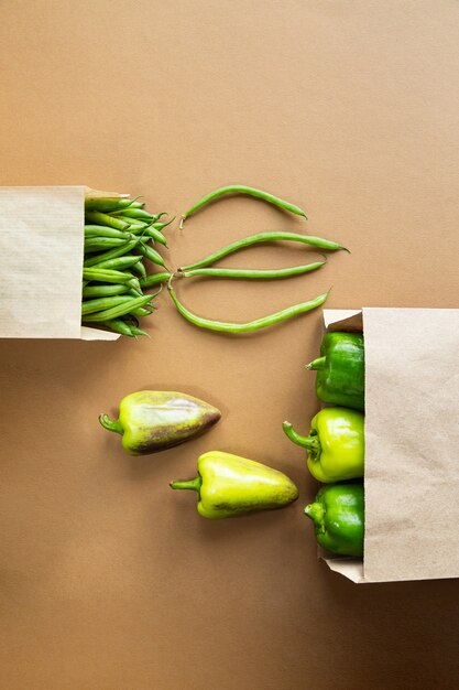 Green beans and paprika in a craft package on a brown desk. Harvest organic healthy food