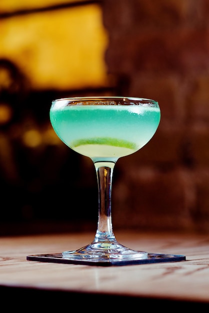 green and blue with lime alcohol cocktail in the glass on the table in bar