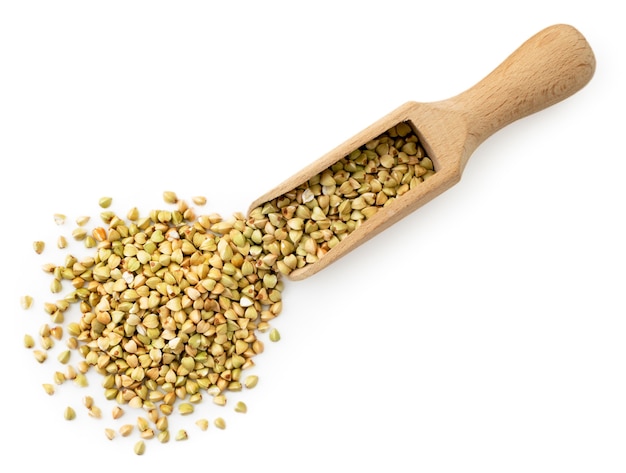 Green buckwheat spilled from a wooden scoop