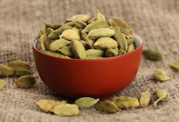 Green cardamon in ceramical bowl on canvas background closeup