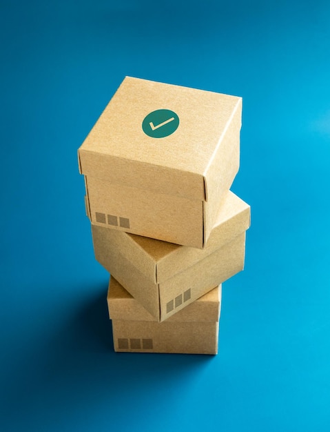 Green check mark icon on lid of cardboard parcel boxes stack on blue background vertical style Carton kraft paper box with lid on top Delivery packaging with online shopping and shipping concepts