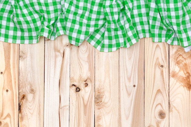 Green checkered tablecloth on wooden table, top view