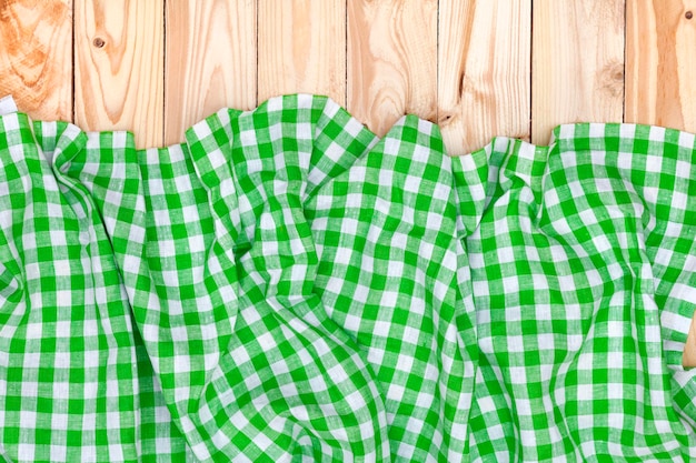 Green checkered tablecloth on wooden table top view