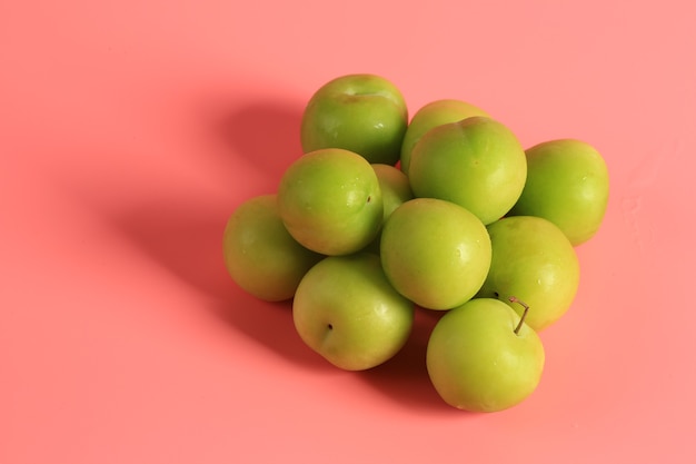 Green cherry plum on a pink background. Creative minimalist style. healthy food