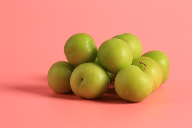 Green cherry plum on a pink background Creative minimalist style healthy food