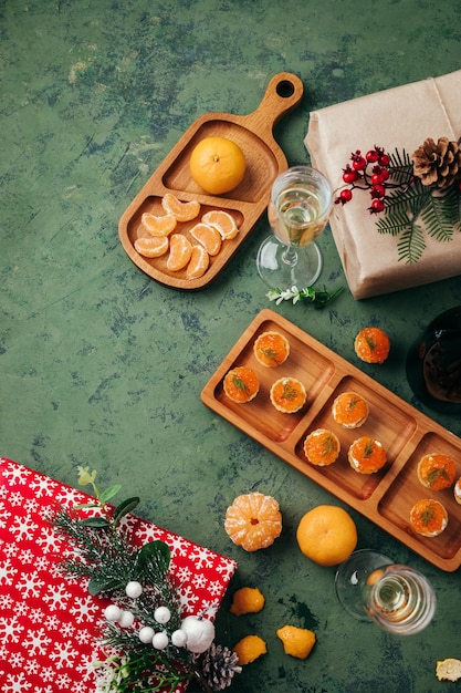 Green christmas background tartlets with red caviar tangerines and champagne