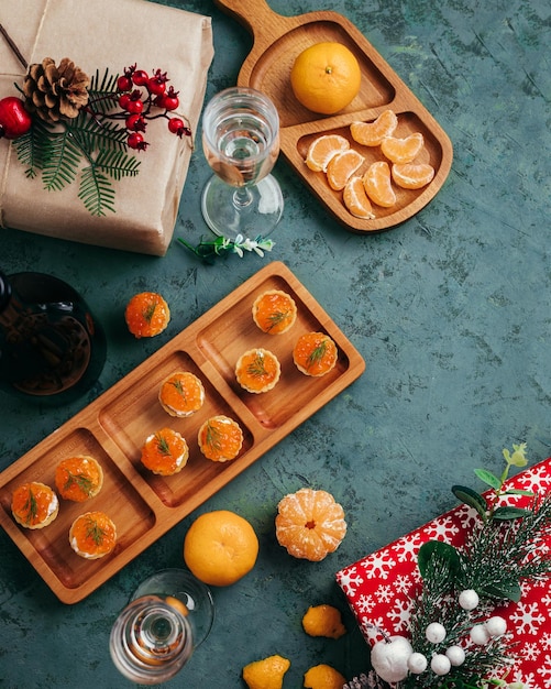 Green christmas background tartlets with red caviar tangerines and champagne