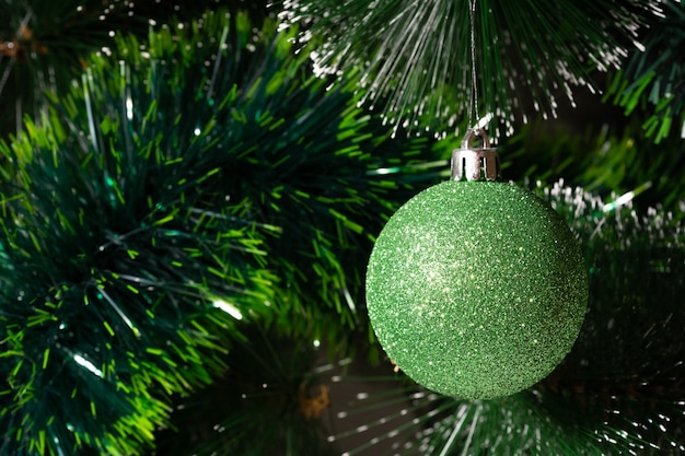 Green Christmas ball hanging on Christmas tree. holiday and new year concept