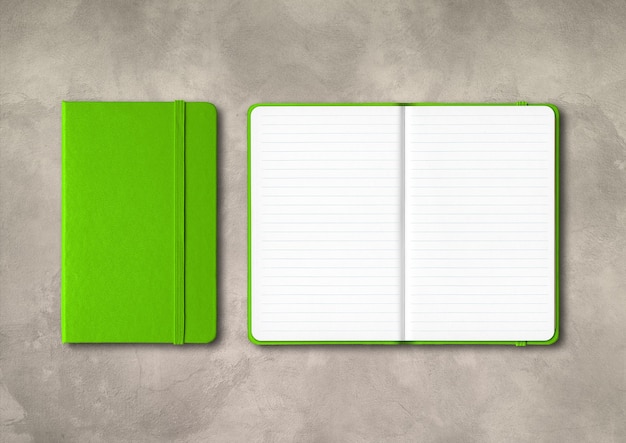 Green closed and open lined notebooks  isolated on concrete background