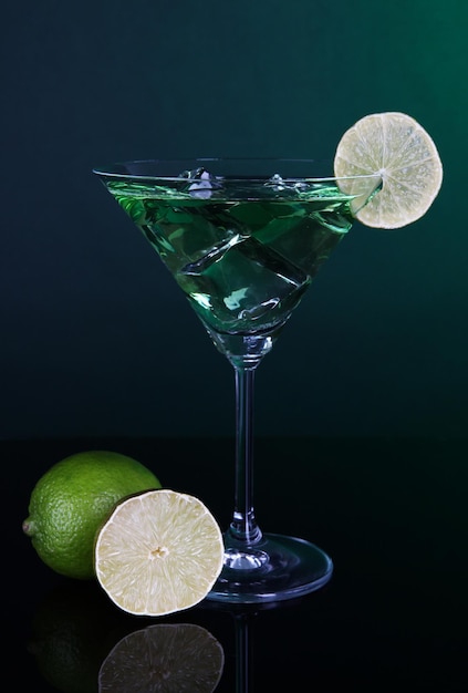 Green cocktail with lime on dark green background