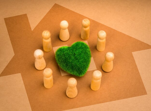 Green common area revitalizing volunteer group cooperation community eco sustainability environment responsibility concepts wooden people figures surround green heart on big home shape background