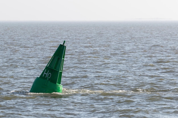 Green conical buoy swims in the North Sea