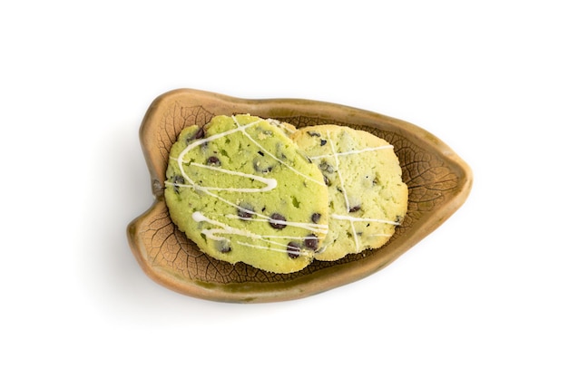 Green cookies with chocolate and mint on leaflike ceramic plate isolated on white background top view close up