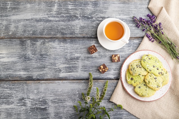 Green cookies with chocolate and mint with cup of green tea on gray wooden background top view copy space