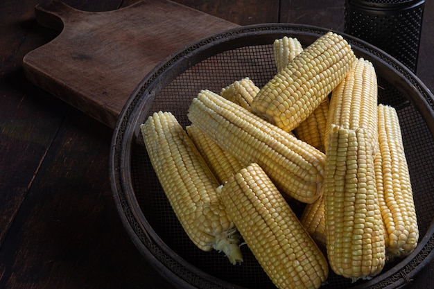 Green corn with sieve on a rustic wooden table