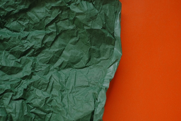 Green crumpled paper on a orange background.