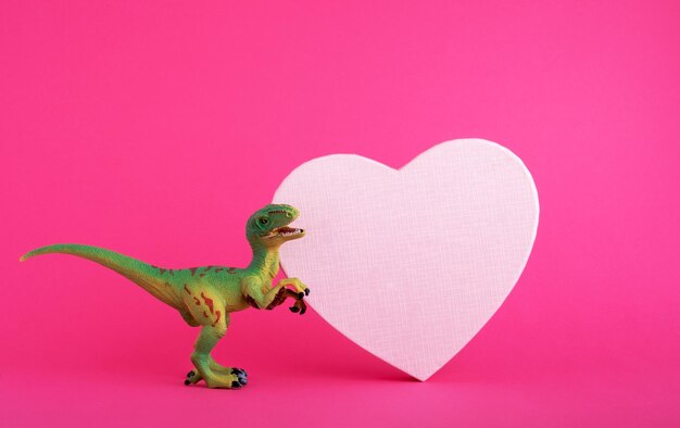 Green cute dinosaur with pink heart on vivid pink background Creative minimal greeting card on Valentines day Love concept