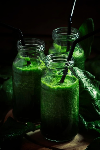 Green detox spinach avocado apple drink smoothies in glass bottle vintage wooden background low key selective focus