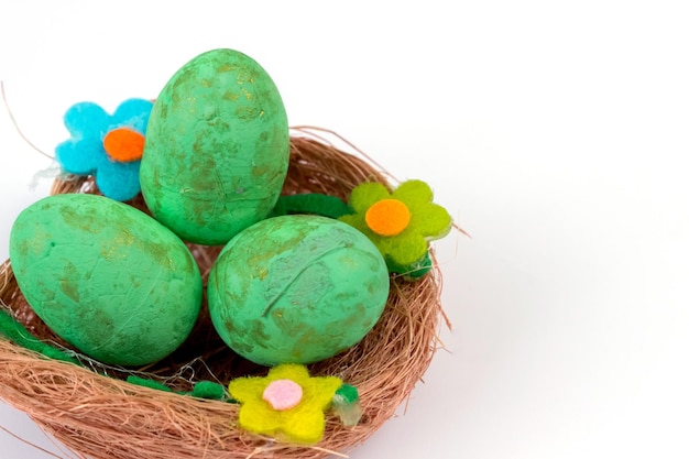 Green Easter eggs in a nest on a white background